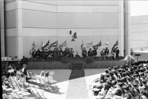 Hold on to your hats! Convocations were often windy affairs on the Ross Terrace. The photo is showing the convocation podium against the wall of the Scott Library. Photo courtesy of York University Libraries, Clara Thomas Archives and Special Collection, ASC19502.